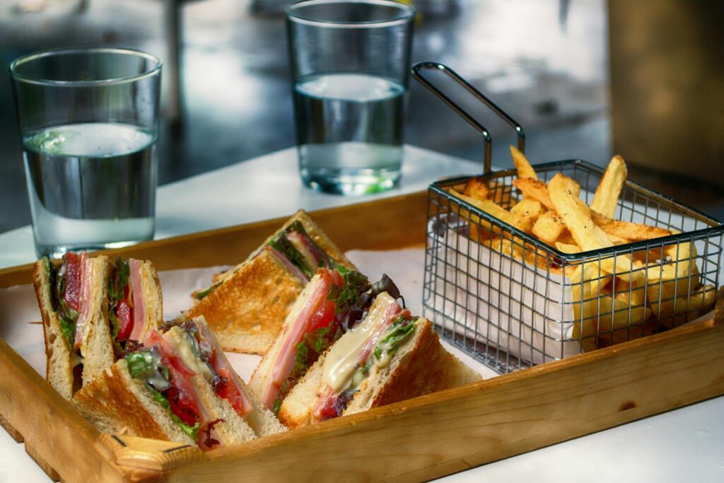 Tasty club sandwich and crispy fries served with glasses of water, perfect for a quick meal.